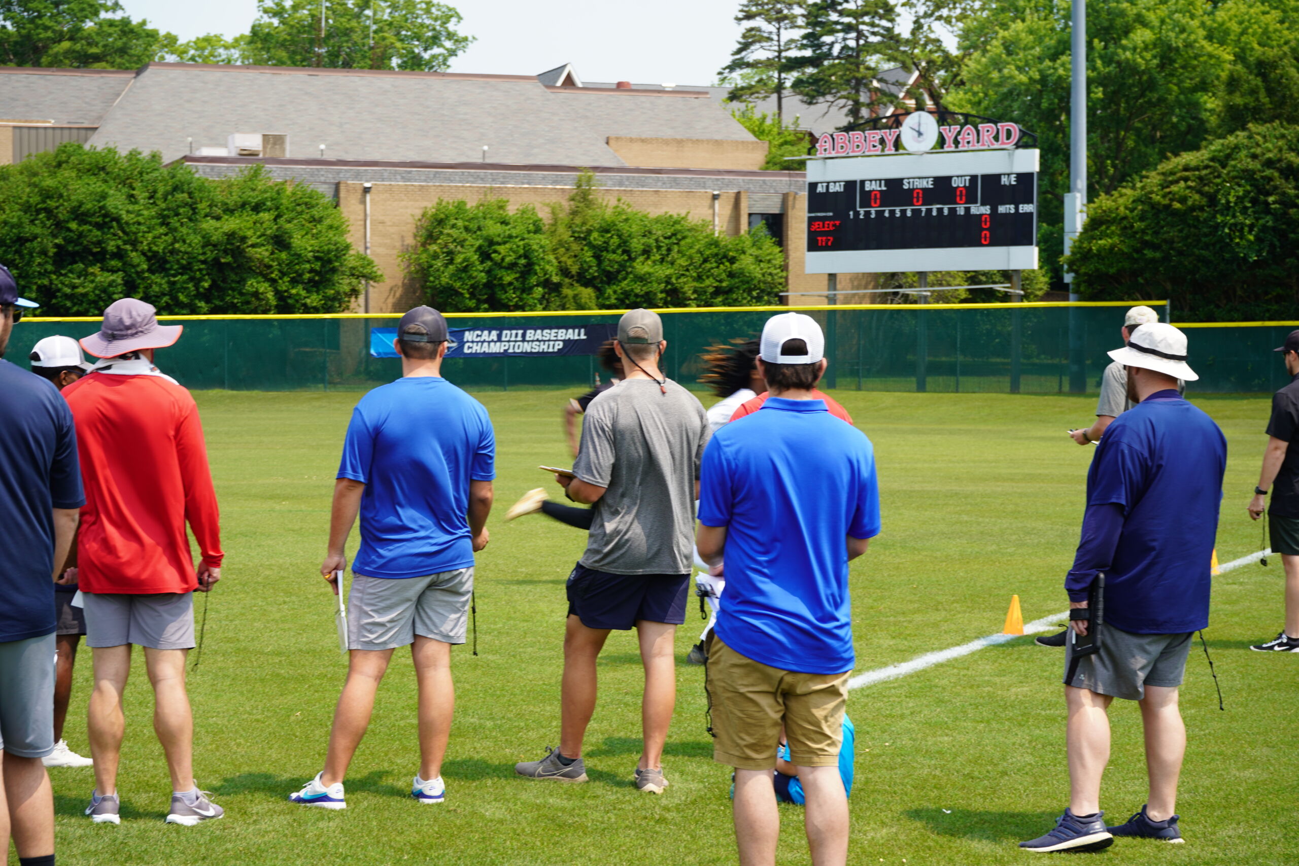 College coaches track player’s 60-yard dash performance with stopwatches and clipboards during timed testing at a Committed Baseball Showcase.
