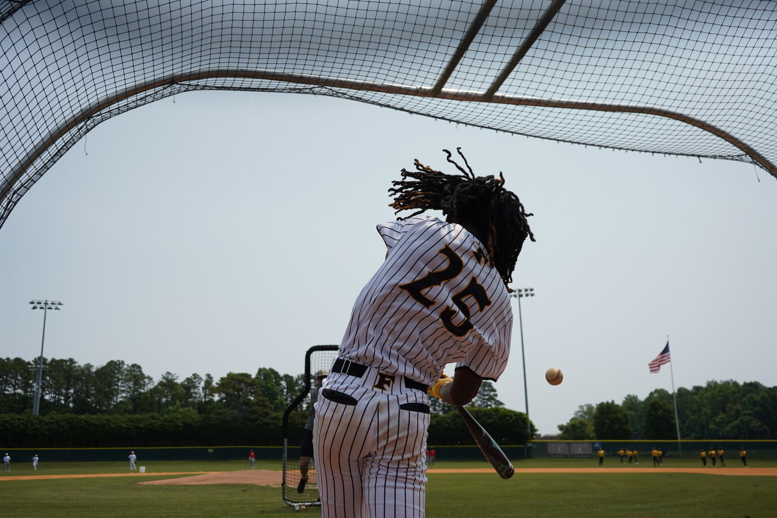 Baseball prospect swings at live pitch during batting practice round at Committed Baseball Showcase, showcasing power in front of coaches.