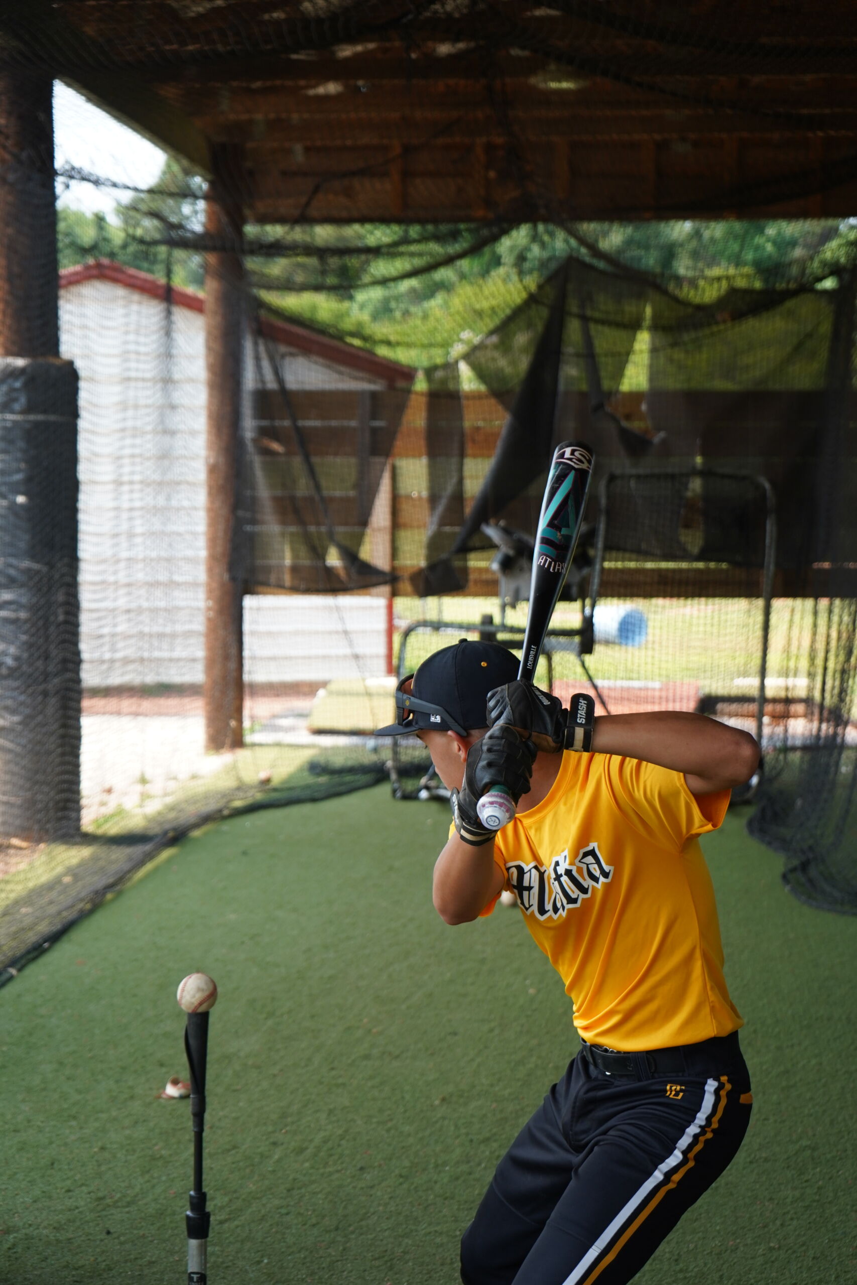 Baseball prospect prepares to swing off a tee with Blast Motion sensor attached, during training session at Committed Baseball Showcase.