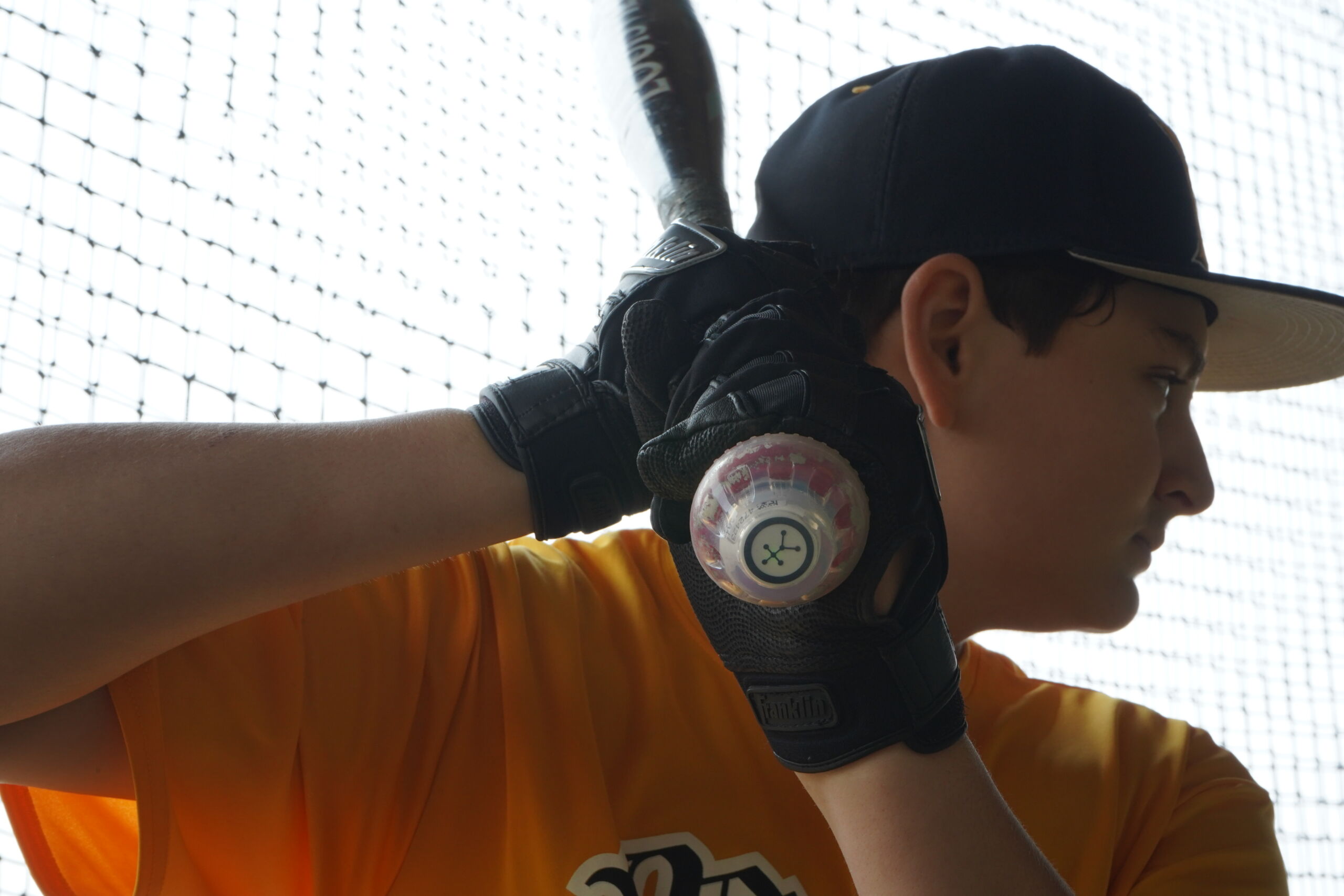Close-up of hitter gripping bat with Blast Motion sensor during swing analysis at Committed Baseball Showcase.
