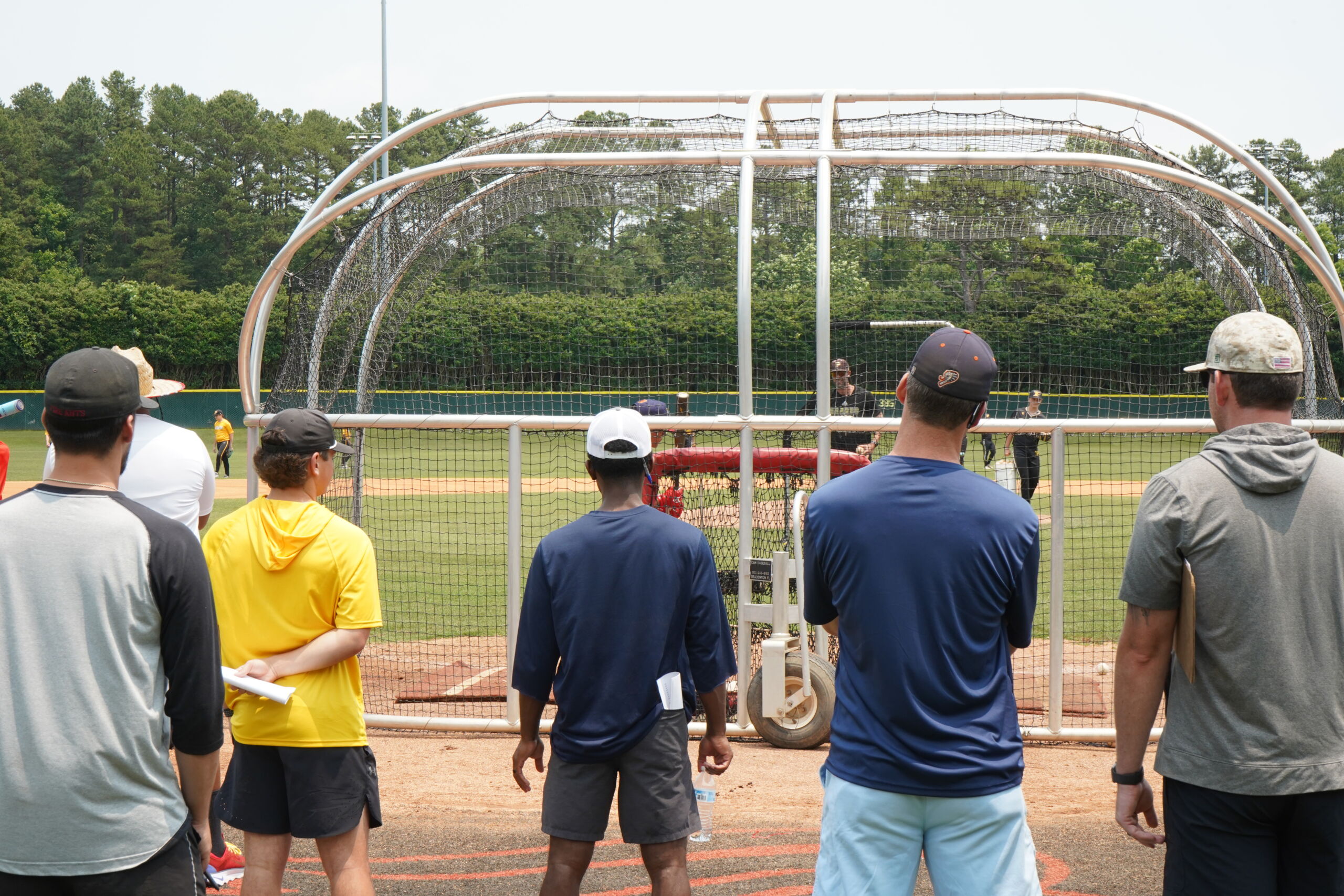 Recruiters and instructors monitor swing mechanics and ball contact from behind home plate at Committed Baseball Showcase.