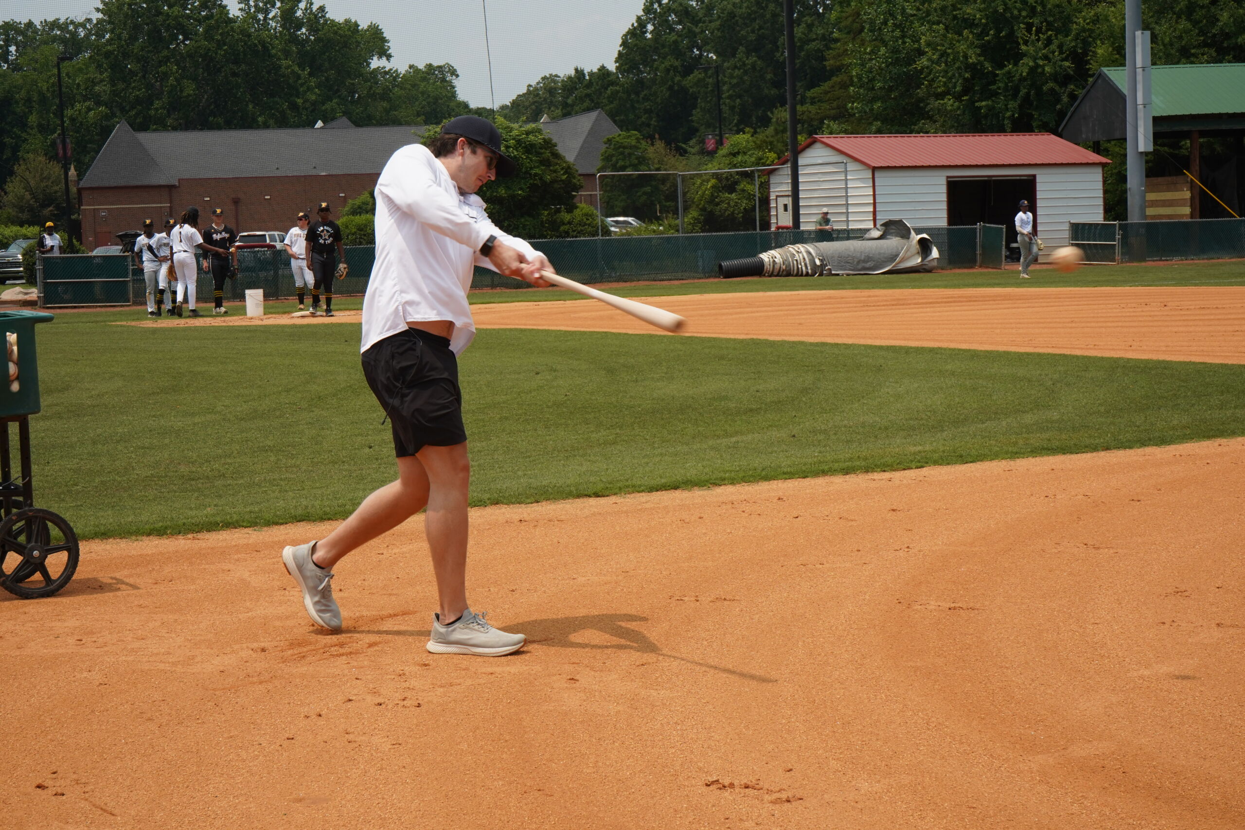 Coach hits ground balls during infield defensive workout at Committed Baseball Showcase as players prepare for fielding evaluations.