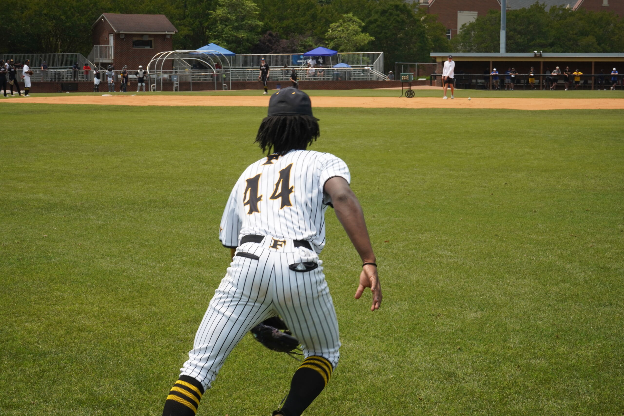 Outfielder tracks fly ball during defensive evaluation at Committed Baseball Showcase as coaches observe from behind infield.